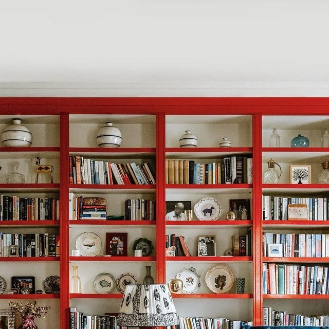 a living room filled with lots of furniture and bookshelves covered in red bookcases