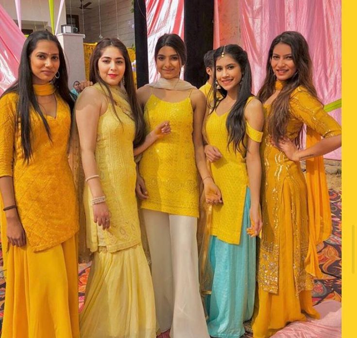 four women in yellow dresses posing for the camera