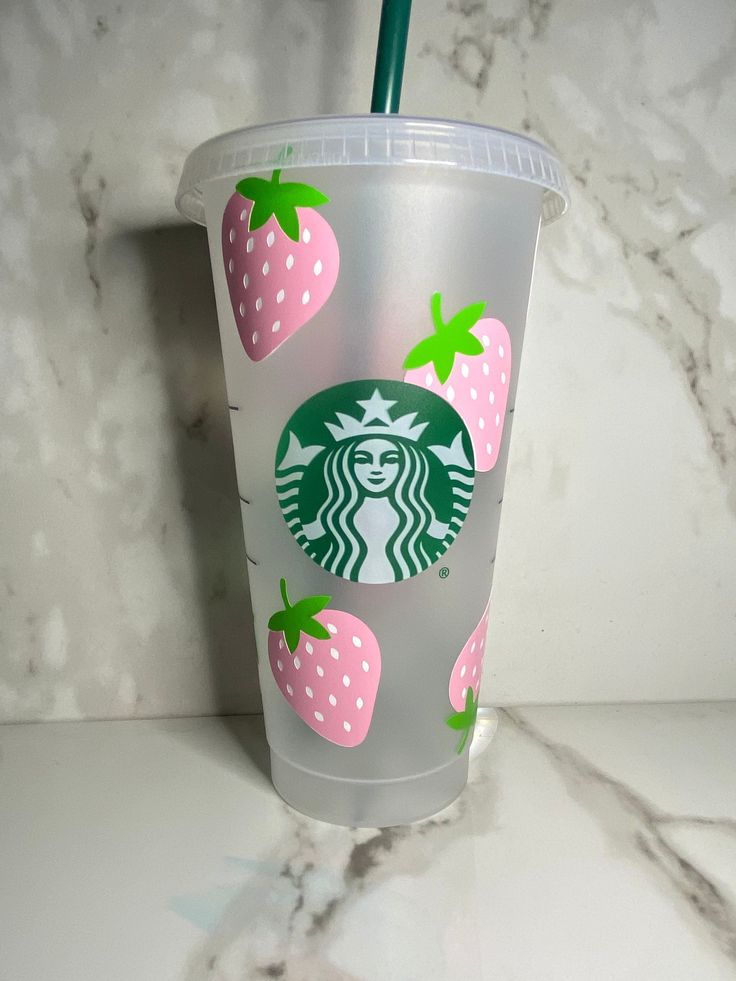 a starbucks cup with strawberries on the side and a green straw sticking out of it