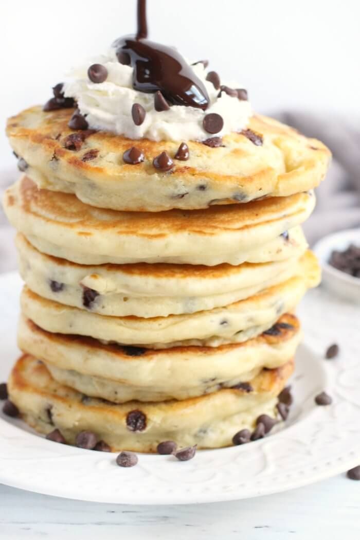 stack of pancakes topped with whipped cream and chocolate chips