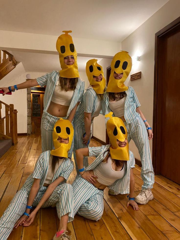 a group of people with masks on their faces posing for a photo in the middle of a room