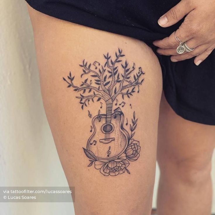 a woman's thigh with a guitar and flowers tattoo on her left side calf