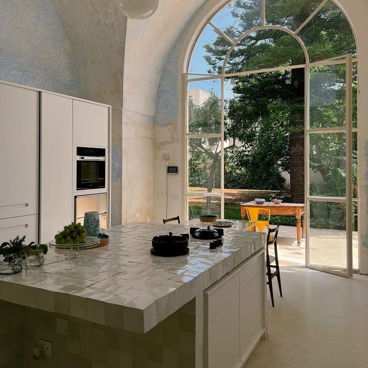 a large kitchen with an arched window and marble counter tops