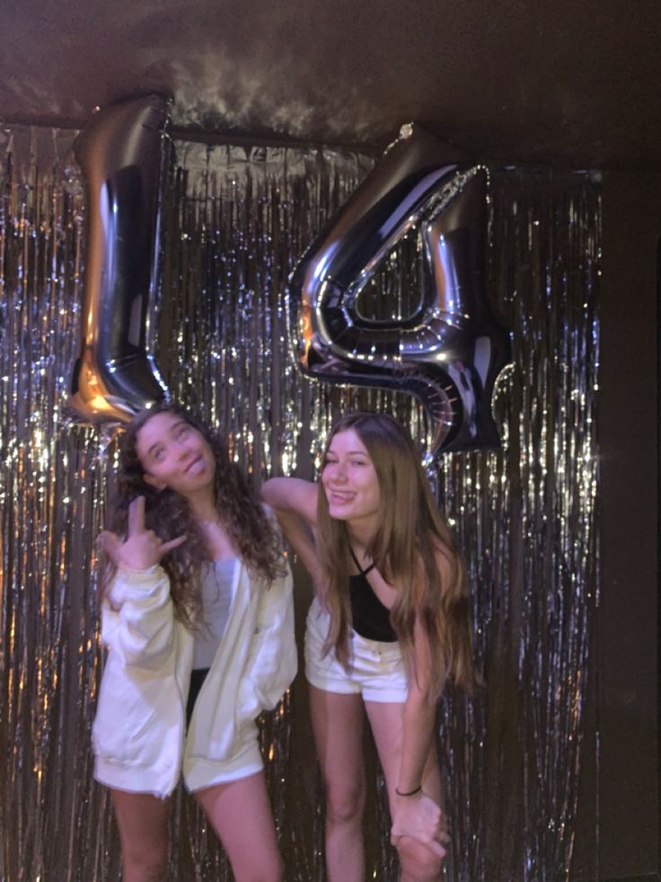 two young women standing next to each other in front of a number four balloon sign