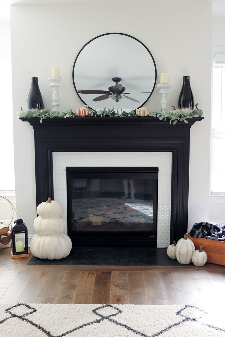 the fireplace is decorated with pumpkins, candles and greenery on it's mantle