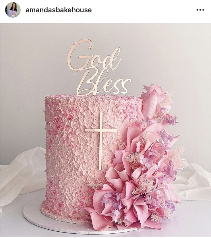 a pink cake decorated with flowers and a cross on top is featured in an instagram