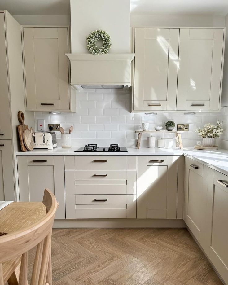 a kitchen filled with lots of white cabinets and counter top space next to a wooden table