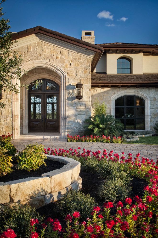 a house with flowers in front of it and a stone wall around the entrance area