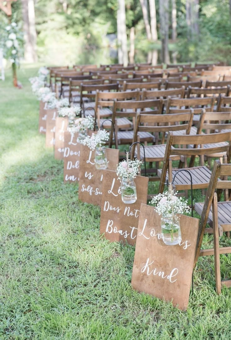 an outdoor ceremony set up with wooden chairs and mason jars filled with baby's breath flowers