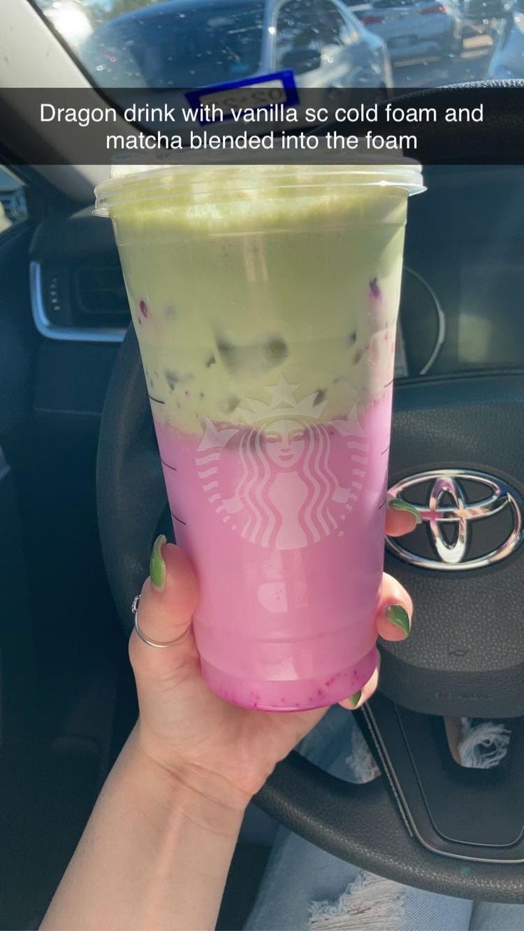 a person holding up a pink and green drink in their hand with the caption dragon drink with vanilla ice cream and matcha blended into the foam