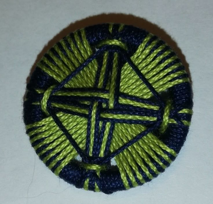 a green and blue brooch sitting on top of a white table