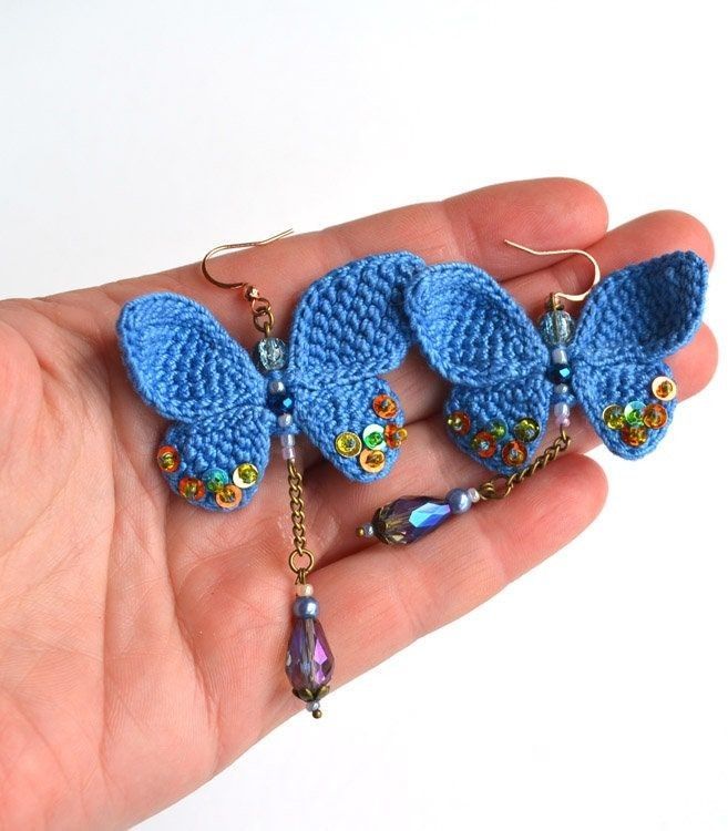 there is a small blue crochet butterfly on the palm of someone's hand