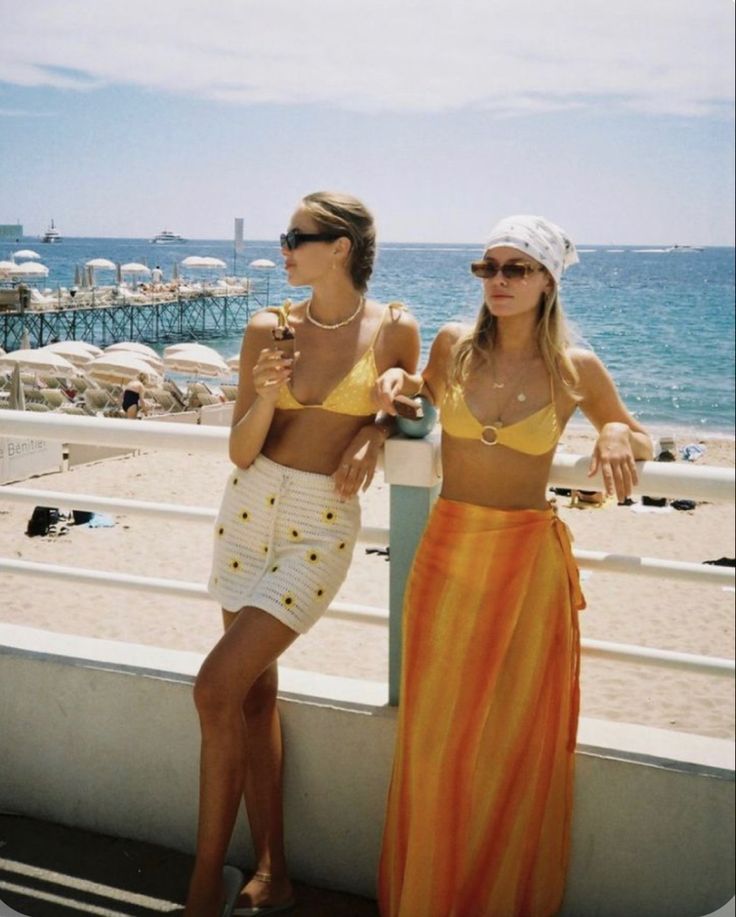 two women standing next to each other on a beach