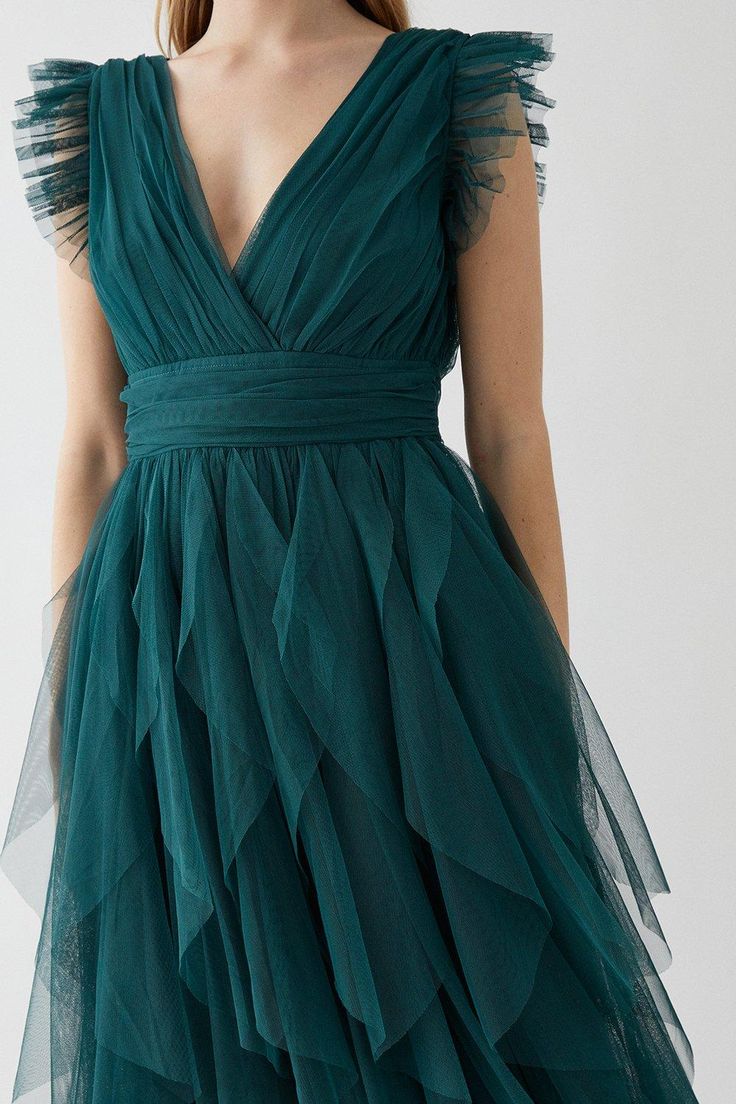 a woman wearing a green dress with ruffles