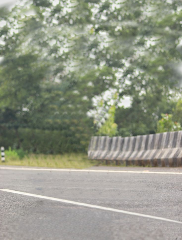 a man riding a skateboard down the side of a road next to a forest