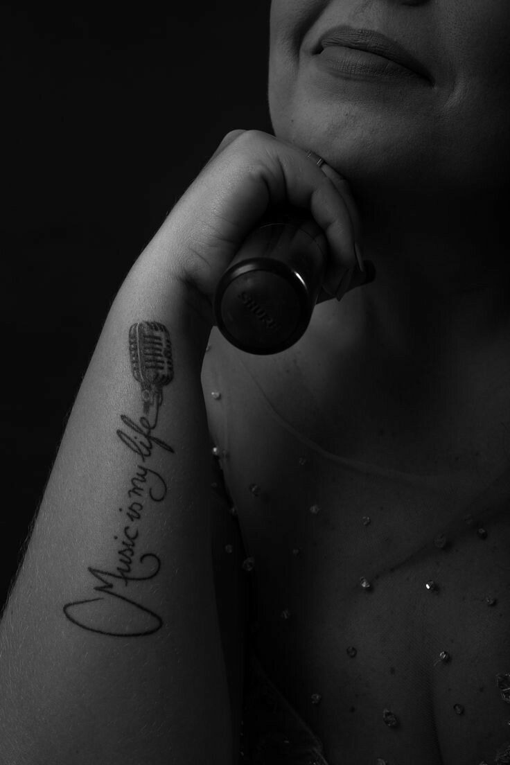 a woman with a tattoo on her arm holding a hair dryer and looking at the camera