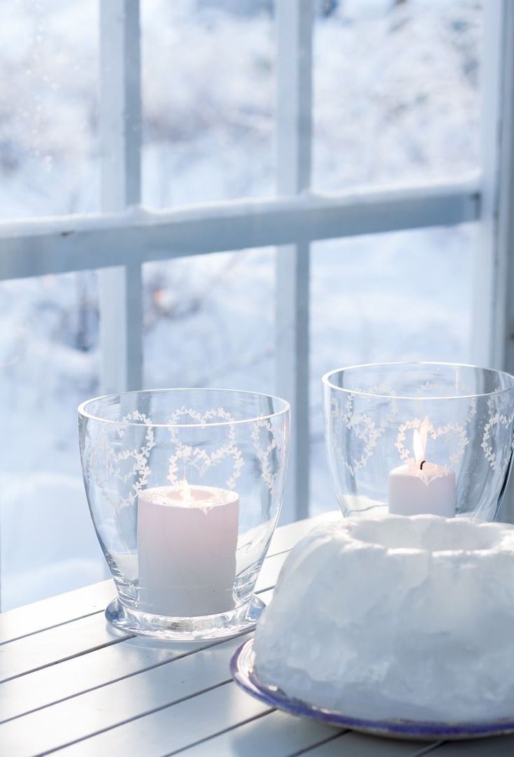 two candles are lit in front of a window