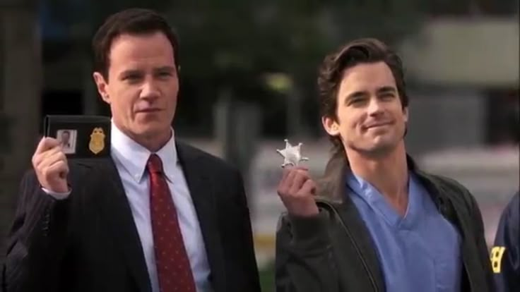 two men in suits and ties holding up small objects