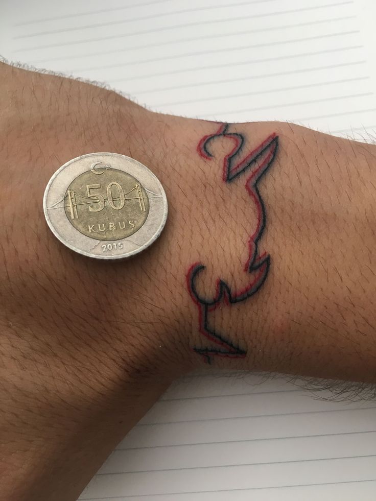 a person's arm with a tattoo on it and a coin in the other hand