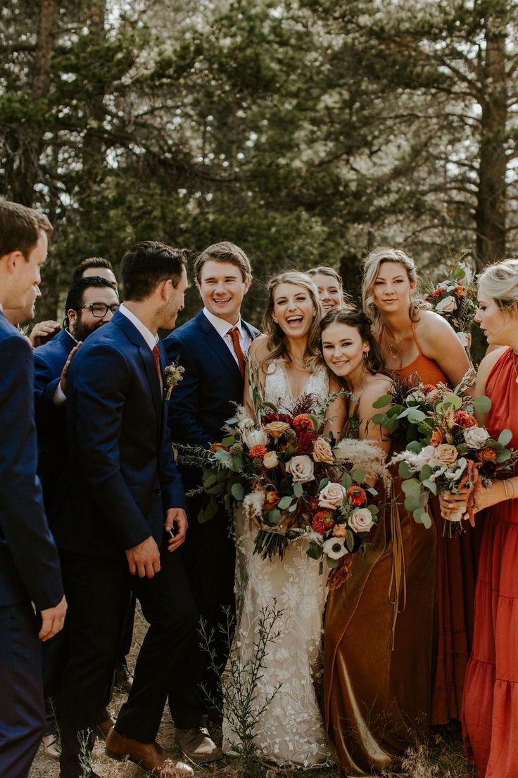 a group of people standing next to each other in front of some trees and bushes