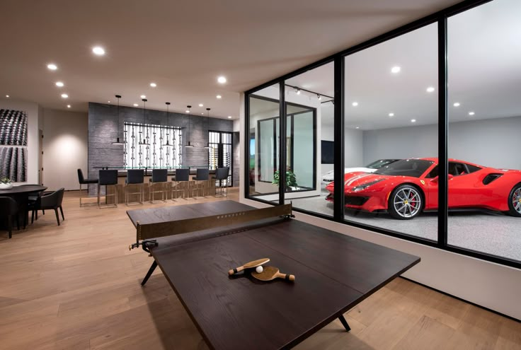 a room with a table, chairs and a red sports car in front of it