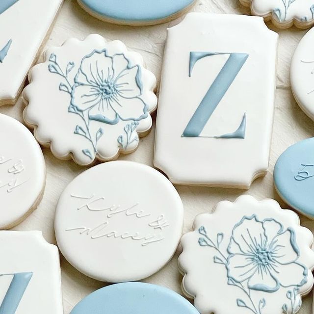 decorated cookies with blue and white frosting are arranged in the shape of letters, numbers, and flowers