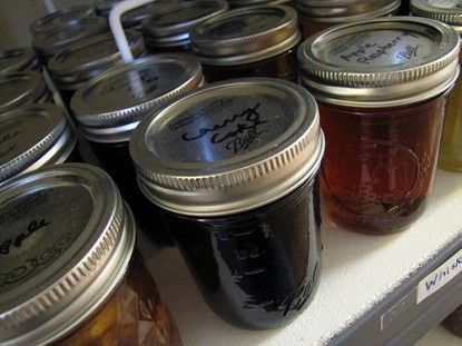 many jars of jam are lined up on a shelf