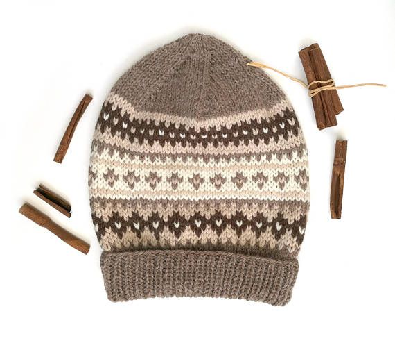 a knitted hat next to cinnamons on a white background with some brown sticks