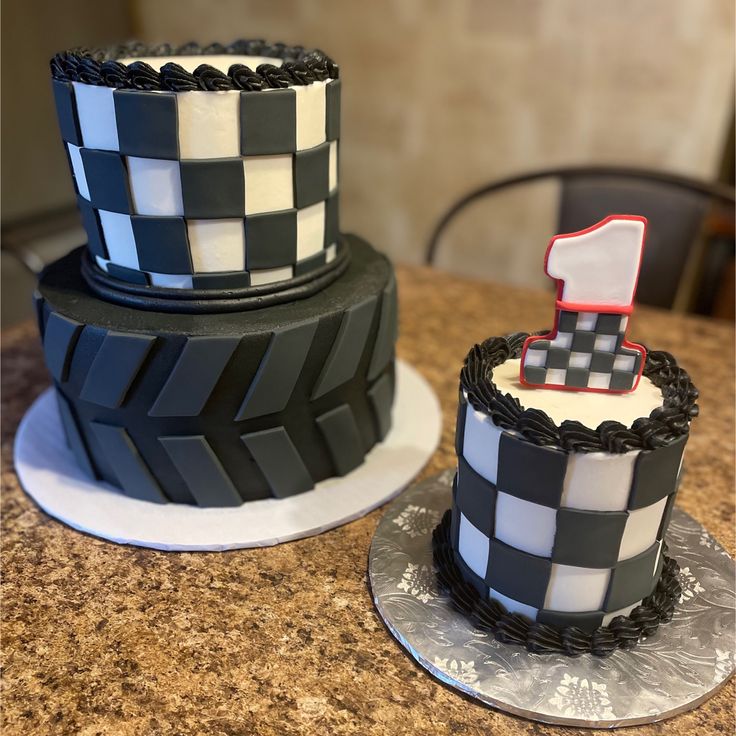 two cakes decorated with black and white checkered icing on top of a table