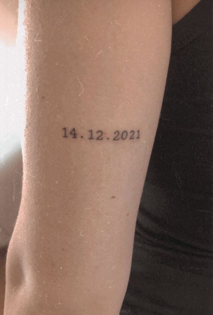 a woman's arm with a date tattooed on the left side of her arm