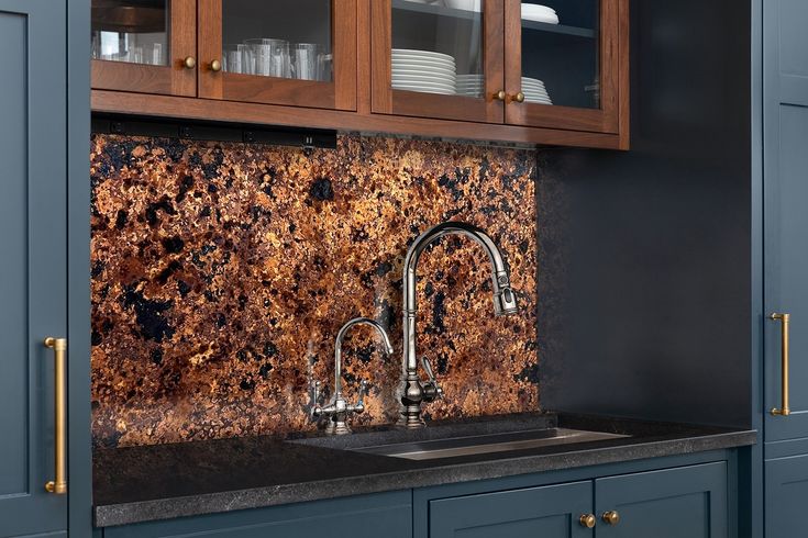 a kitchen with blue cabinets and marble backsplash in the center, along with brass pulls