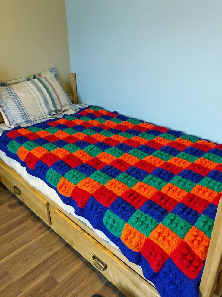 a bed with an orange, green and blue blanket sitting on it's side