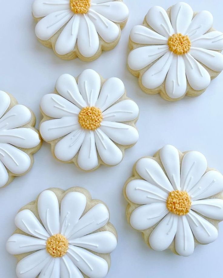 decorated cookies with white icing and yellow centers are arranged in the shape of daisies