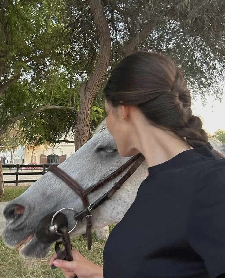 a woman is holding the bridle of a horse in front of her face