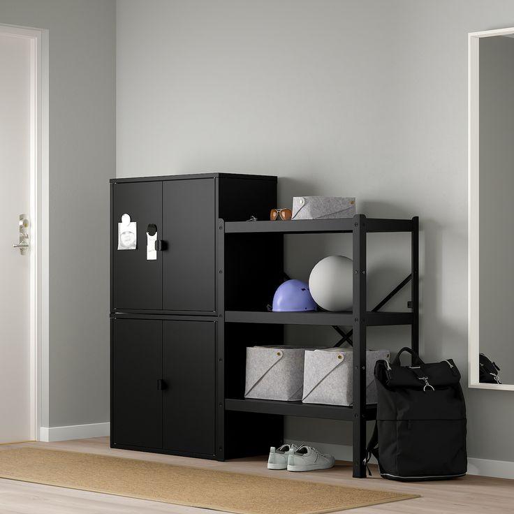 a black bookcase with several different items on it and a bag next to it