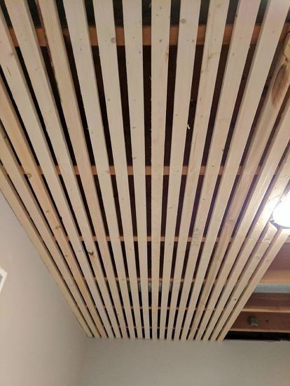 the ceiling is made out of wooden slats and has been stripped off with paint