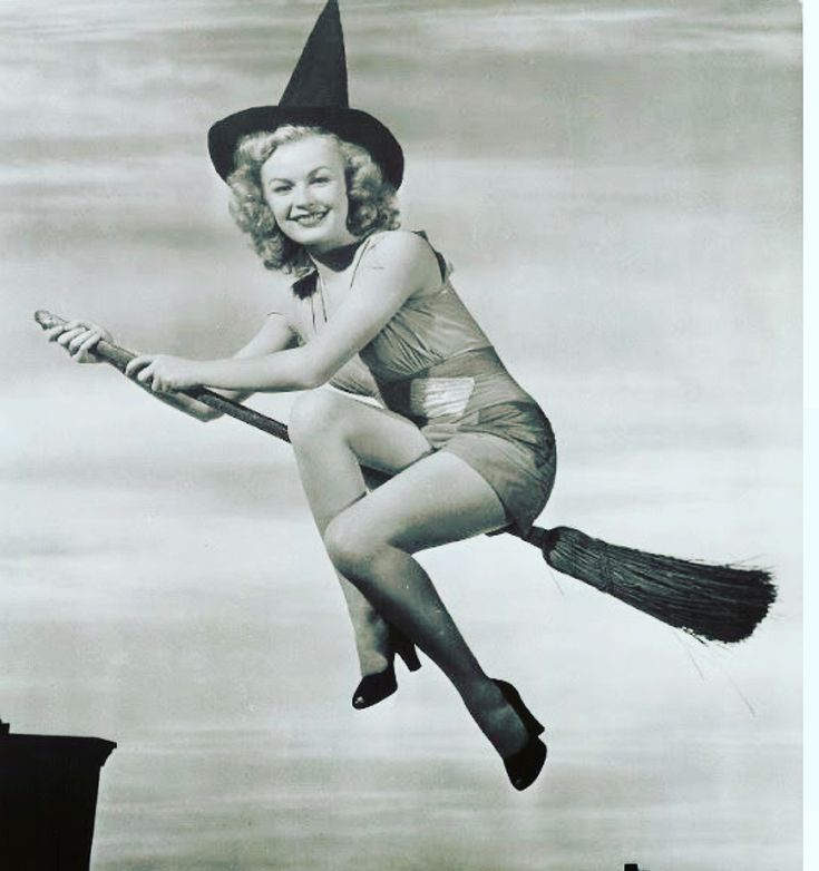 an old photo of a woman dressed as a witch flying through the air with a broom