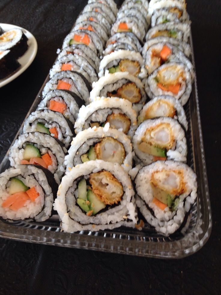 there are many different sushi rolls on the tray and one is ready to be eaten