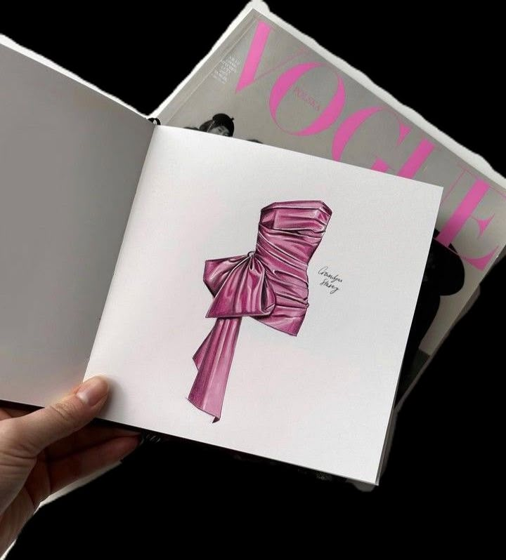 a hand holding an open book with a pink bow on the front and back cover