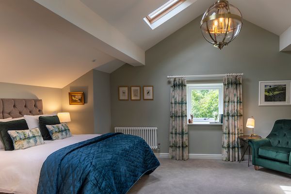 a bedroom with a bed, chair and window in it's center wall is shown