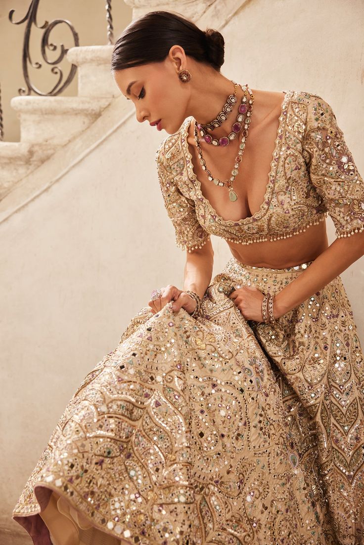 Step into timeless elegance with this exquisite champagne raw silk lehenga set. Intricately adorned with embroidery in zardosi, sequin, mirror, resham, and beads, each detail exudes opulence and charm. Paired with an elbow sleeve length blouse and a delicate tulle dupatta, this ensemble offers the perfect blend of sophistication and grace. Make a statement with this captivating ensemble, showcasing traditional craftsmanship and contemporary allure. Luxury Embellished Chanderi Lehenga, Luxury Traditional Chinon Lehenga, Luxury Chikankari Embroidered Lehenga For Reception, Luxury Chanderi Lehenga For Reception, Luxury Art Silk Lehenga With Chikankari Embroidery, Lehenga Fits, Zardosi Lehenga, Indian Formals, Indian Reception Outfit