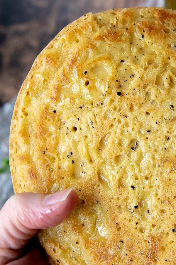 a person holding up a piece of bread with cheese on it's crusts