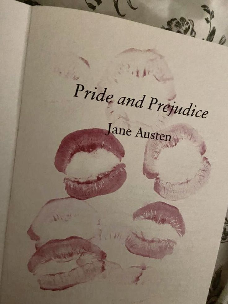 a book with lipstick drawn on it sitting on top of a bed next to pillows