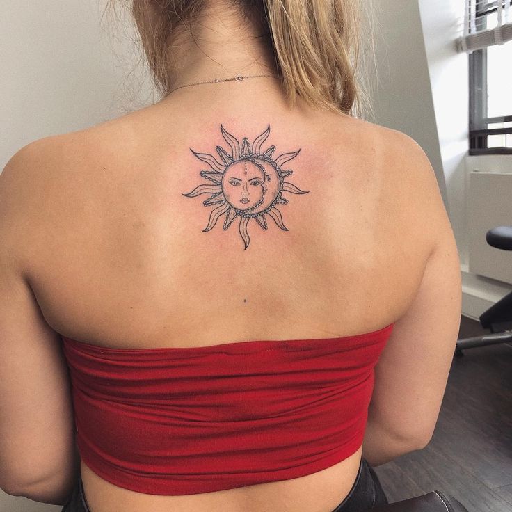 a woman with a sun tattoo on her upper back shoulder and behind her is a red top