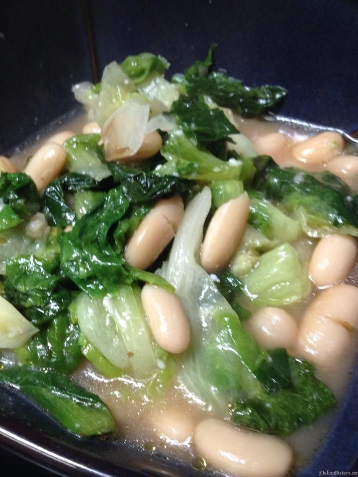 a bowl filled with beans and greens on top of a table