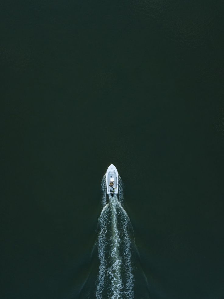 an aerial view of a boat in the water with its wake behind it, taken from above