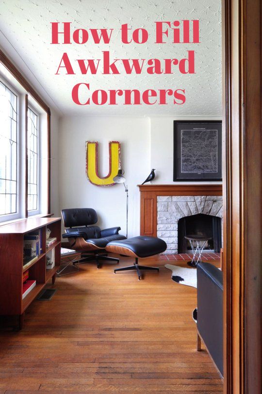 an empty living room with wood floors and a fire place in the corner that has a large u sign on the wall