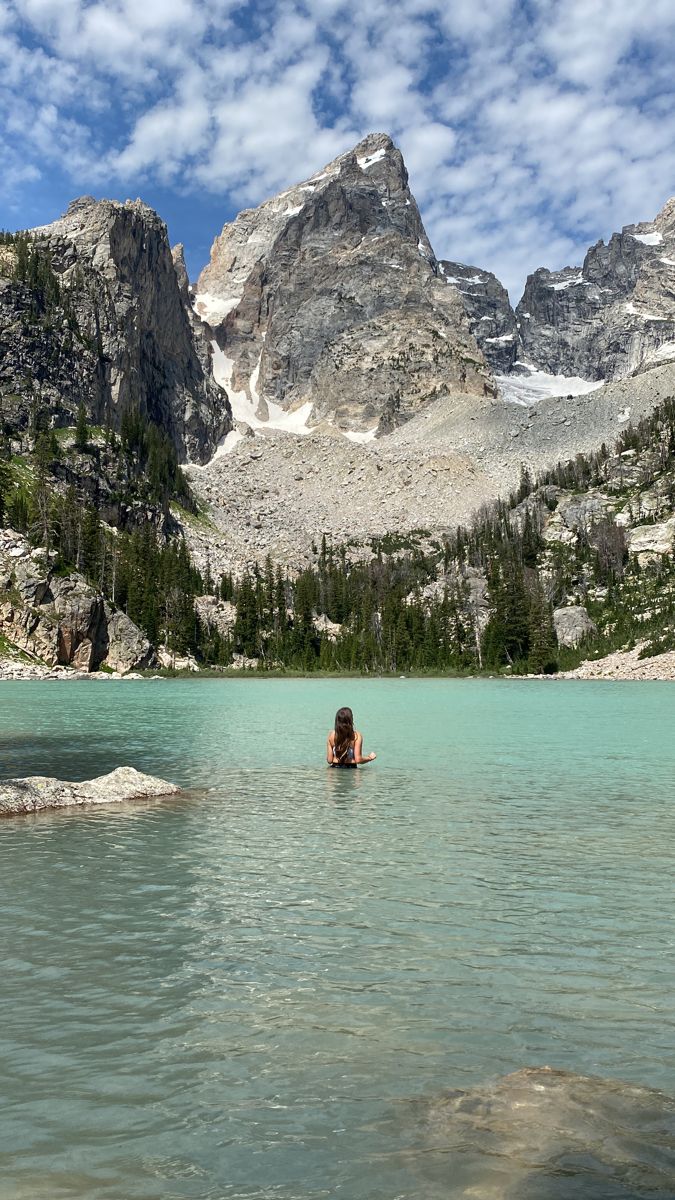 a person swimming in a lake with mountains in the background