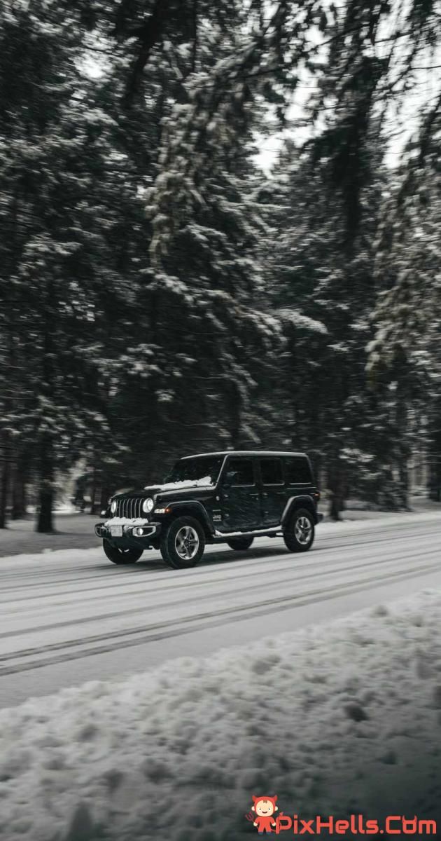 a black jeep driving down a snow covered road