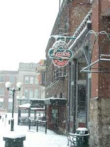 a restaurant sign hanging from the side of a brick building covered in snow and ice